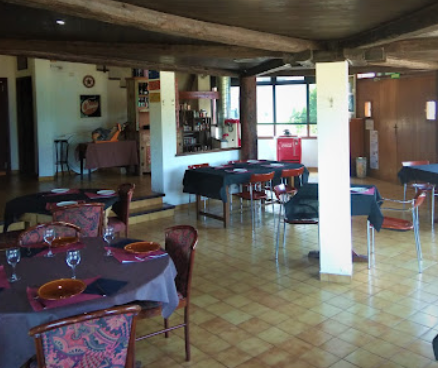 El comedor con las mesas puestas, vigas de madera y la barra al fondo