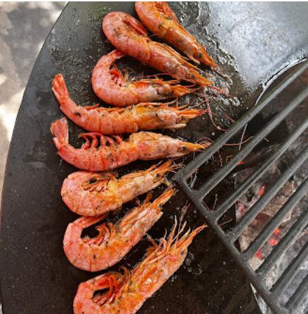 Hilera de gambas chisporroteando en la parrilla circular