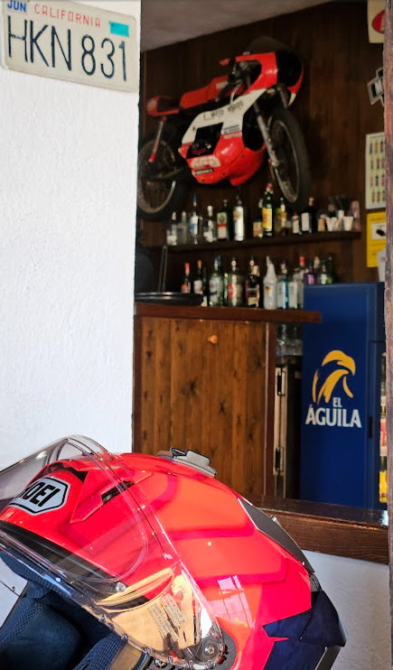 Casco Shoei rojo, matrícula de California y moto de carreras sobre la barra